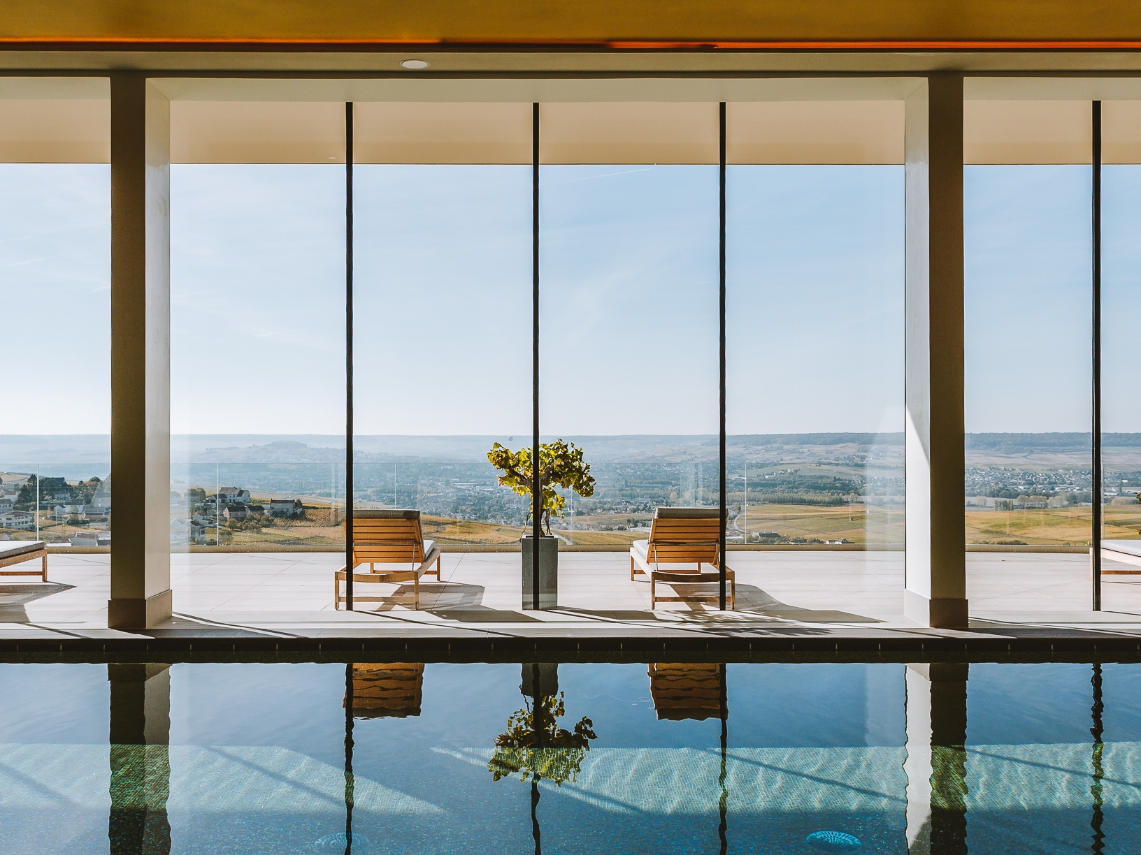 Indoor pool with floor-to-ceiling windows over the Champagne countryside